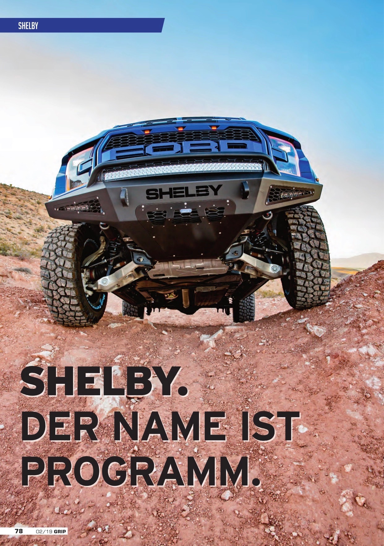GRIP — Shelby. Der Name ist Programm. page 78, dramatic low-angle front shot of blue Shelby Baja Raptor on desert rock